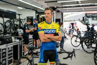 Cycliste professionnel WorldTour debout près de son vélo dans un garage d'équipe, reflétant les négociations de transfert 2026