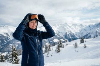 Skieuse ajustant ses lunettes de ski correctrices au sommet d'une piste alpine enneigée