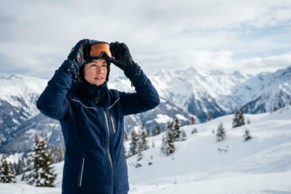 Skieuse ajustant ses lunettes de ski correctrices au sommet d'une piste alpine enneigée